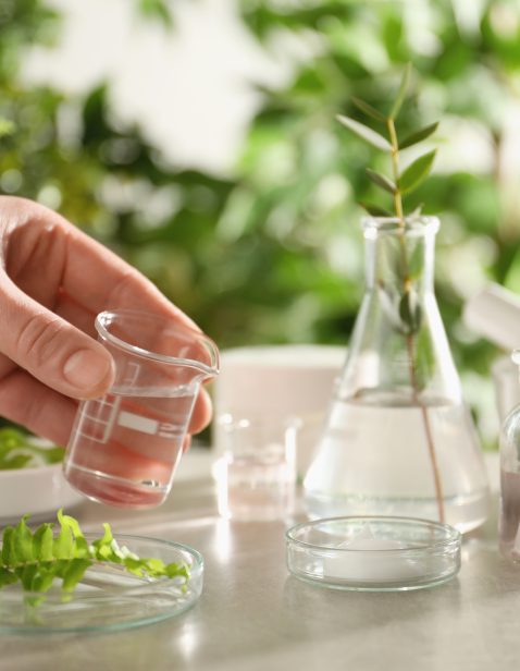 Scientist making cosmetic product at grey table, closeup