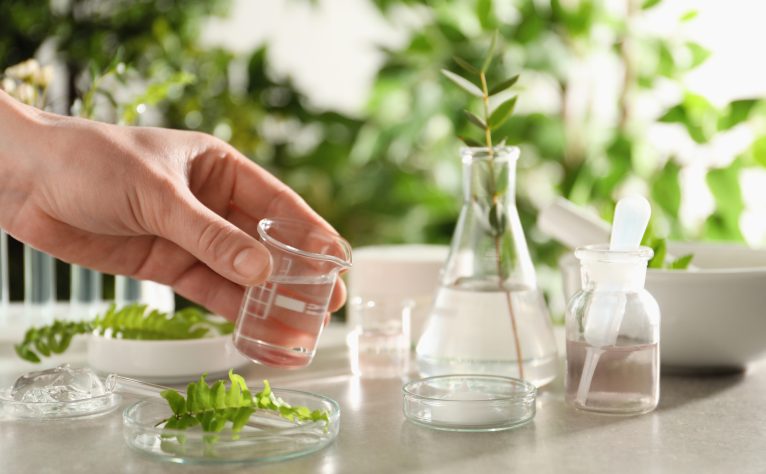 Scientist making cosmetic product at grey table, closeup